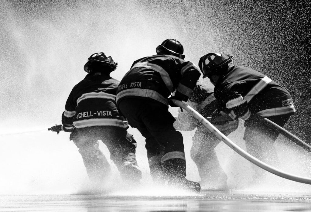 Firefighters in full gear battle heavy water spray in an intense operation.